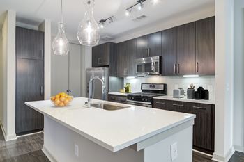 A modern kitchen with a white island and dark wood cabinets.